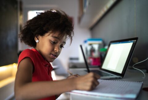 Young girl studying at home, writing in note pad